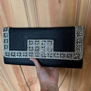 Jeweled black clutch with metal shoulder strap.